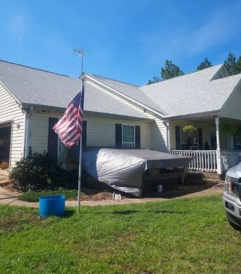 Residential home with gray shingle roof and American flag in front yard