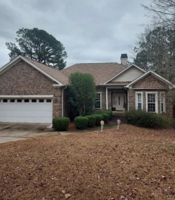 Brick suburban home with asphalt shingle roof, attached garage, and front yard